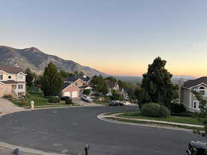 View of asphalt road featuring curbs, a mountain view, and sidewalks