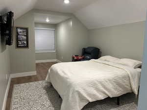 Bedroom featuring a textured ceiling, wood finished floors, and lofted ceiling