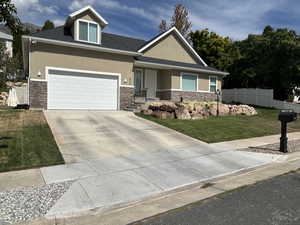 Craftsman-style house featuring stucco siding, covered porch, stone siding, concrete driveway, and a garage