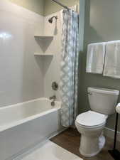 Full bath featuring shower / tub combo with curtain and wood finished floors