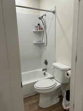 Bathroom featuring washtub / shower combination and light wood-type flooring
