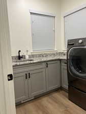 Laundry area with washer / clothes dryer, cabinet space, and light wood-style floors