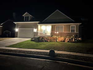 Craftsman house with concrete driveway, stone siding, a yard, and a garage