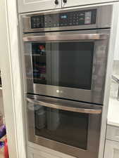 Kitchen view of stainless steel double oven and light stone countertops