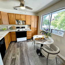 Kitchen with light countertops, electric range, brown cabinets, a textured ceiling, and black dishwasher