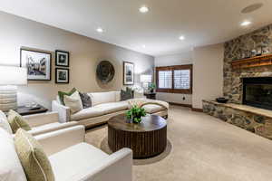 Carpeted living room featuring a stone fireplace and recessed lighting
