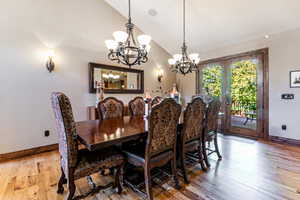 Dining space with vaulted ceiling, light wood finished floors, french doors, and a chandelier