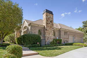 View of front of home featuring brick siding, a front yard, a chimney, roof with shingles, and an attached garage