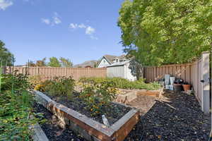 Fenced backyard featuring a shed and a garden