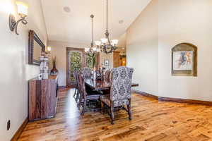 Dining space with light wood finished floors, high vaulted ceiling, and a chandelier
