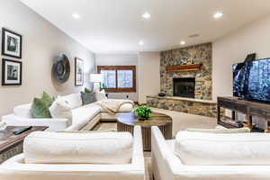 Living area with recessed lighting, a stone fireplace, and carpet floors