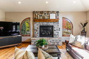 Living room featuring recessed lighting, hardwood / wood-style floors, and a stone fireplace