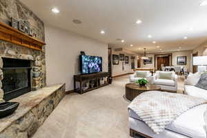 Carpeted living room with recessed lighting and a stone fireplace