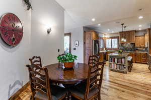 Dining area with light wood finished floors and recessed lighting