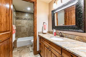 Full bathroom featuring vanity, shower / bathtub combination, and light stone finish floors