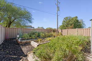 Fenced backyard featuring a vegetable garden