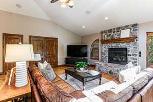 Living room with vaulted ceiling, a fireplace, wood finished floors, and recessed lighting
