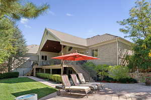 Back of property featuring stairs, a lawn, brick siding, and a patio area