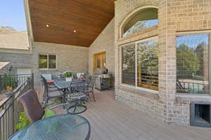 Wooden deck featuring outdoor dining area and a grill