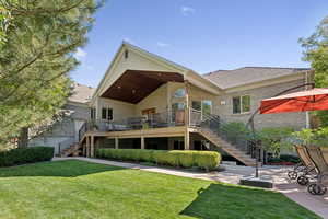 Back of house featuring stairs, brick siding, a lawn, and a shingled roof