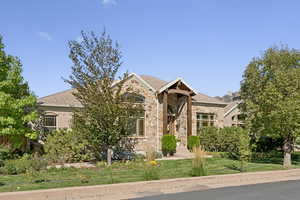 View of front facade with a front yard and stone siding