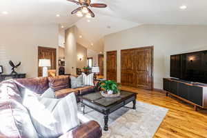 Living room with light wood-style flooring, recessed lighting, high vaulted ceiling, and a ceiling fan