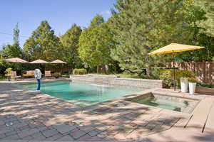 View of swimming pool with a fenced backyard, a patio, and an in-ground hot tub
