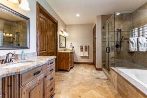 Full bath with two vanities, a bath, a stall shower, and recessed lighting