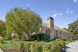 View of front of property with brick siding, a front yard, and a chimney