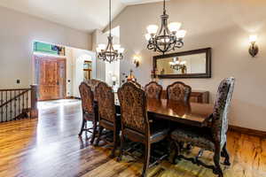 Dining area with lofted ceiling, arched walkways, light wood-style flooring, and a chandelier