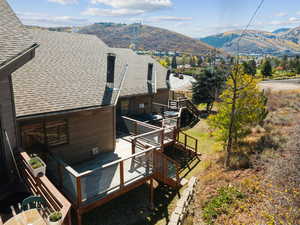 Back of house with a shingled roof, stairway, and a deck with mountain view