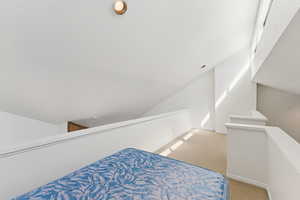 Bedroom with carpet floors and vaulted ceiling