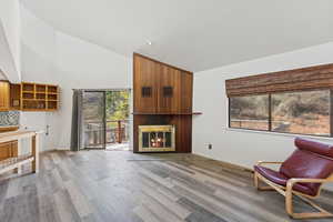 Sitting room featuring high vaulted ceiling, a large fireplace, and light wood-style floors