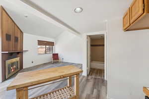 Office space with a fireplace, light wood-type flooring, and lofted ceiling