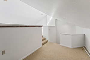 Bonus room featuring carpet, lofted ceiling, and a textured ceiling