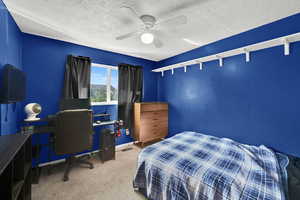 Bedroom with carpet floors, a textured ceiling, ceiling fan, and a desk