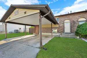 View of front of house with a patio, a carport, driveway, and brick siding