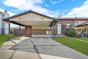 View of front facade featuring brick siding, concrete driveway, and a carport