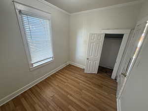 Unfurnished bedroom with a closet, light wood finished floors, and crown molding