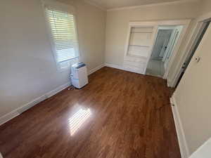 Unfurnished bedroom featuring dark wood-type flooring and ornamental molding