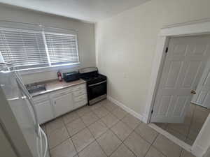Kitchen featuring white cabinets, stainless steel range with gas cooktop, light tile patterned floors, and light countertops
