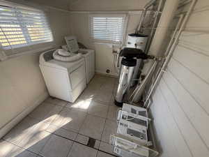 Washroom with light tile patterned floors, separate washer and dryer, and electric water heater
