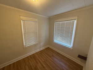 Unfurnished room with crown molding and wood finished floors