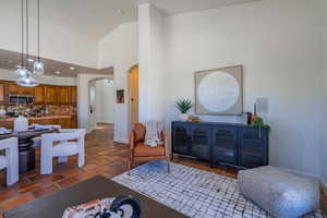 Living room featuring high vaulted ceiling, recessed lighting, arched walkways, and dark tile patterned flooring