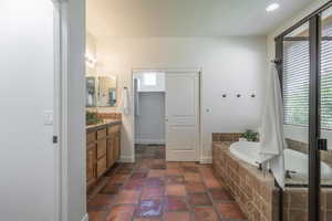 Bathroom with a garden tub, vanity, recessed lighting, and decorative backsplash