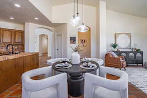 Dining space with recessed lighting, arched walkways, high vaulted ceiling, and a textured ceiling