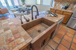 Kitchen view of light countertops, decorative backsplash, brown cabinets, and french doors