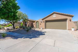 Single story home with stucco siding, driveway, a tiled roof, and an attached garage