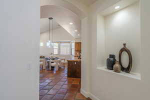 Hallway with vaulted ceiling, recessed lighting, and arched walkways