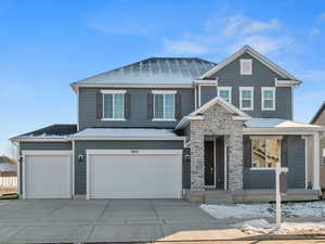 View of front facade with driveway, an attached garage, stone siding, and covered porch